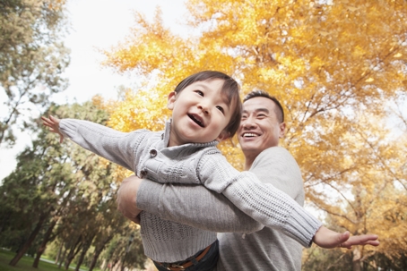 father and son playing outside during fall
