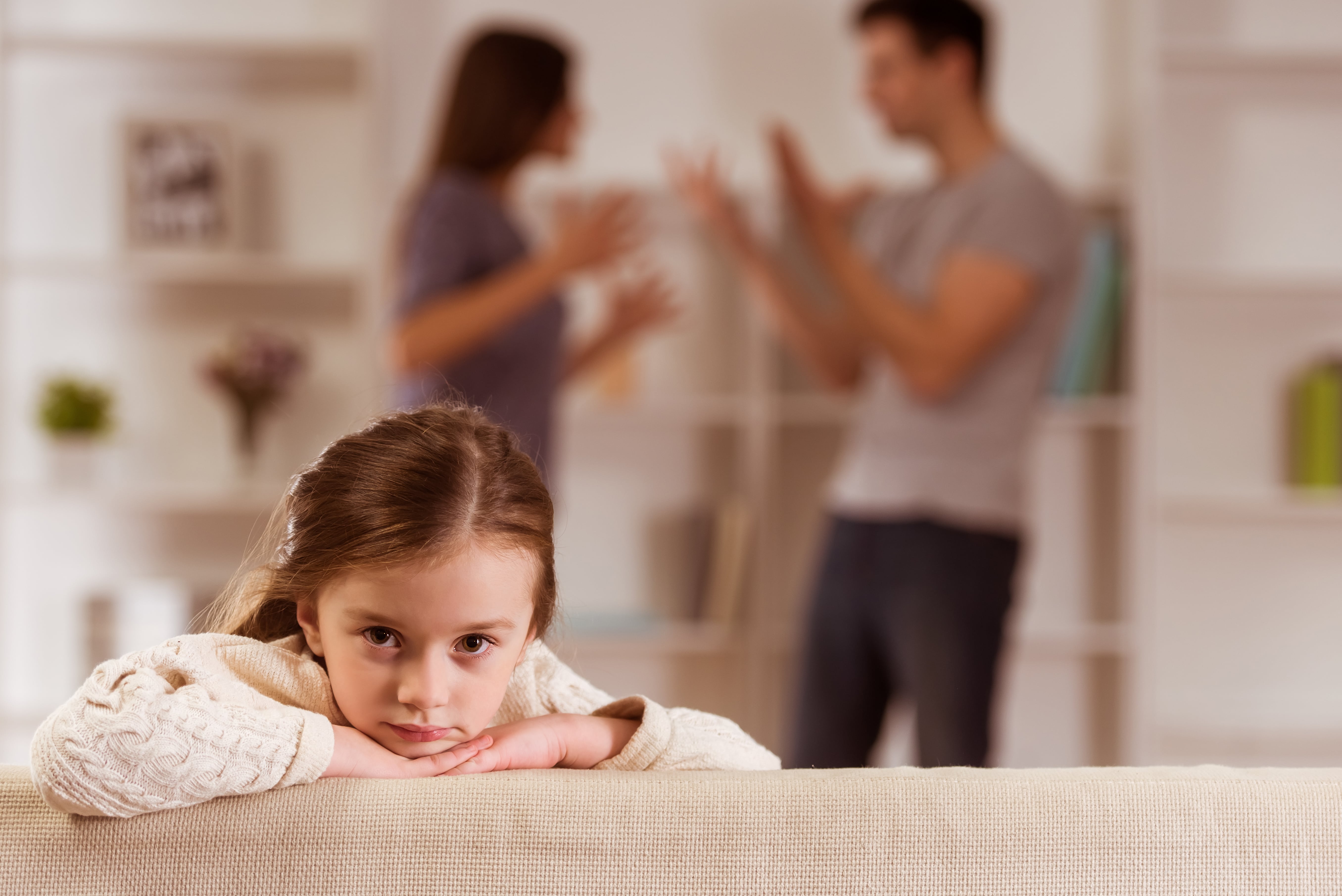 girl with parents arguing in the background